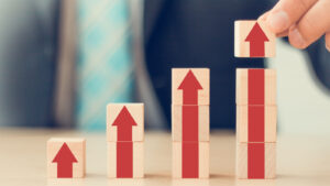 A businessman's hand arranging wooden cube blocks to represent growth stocks